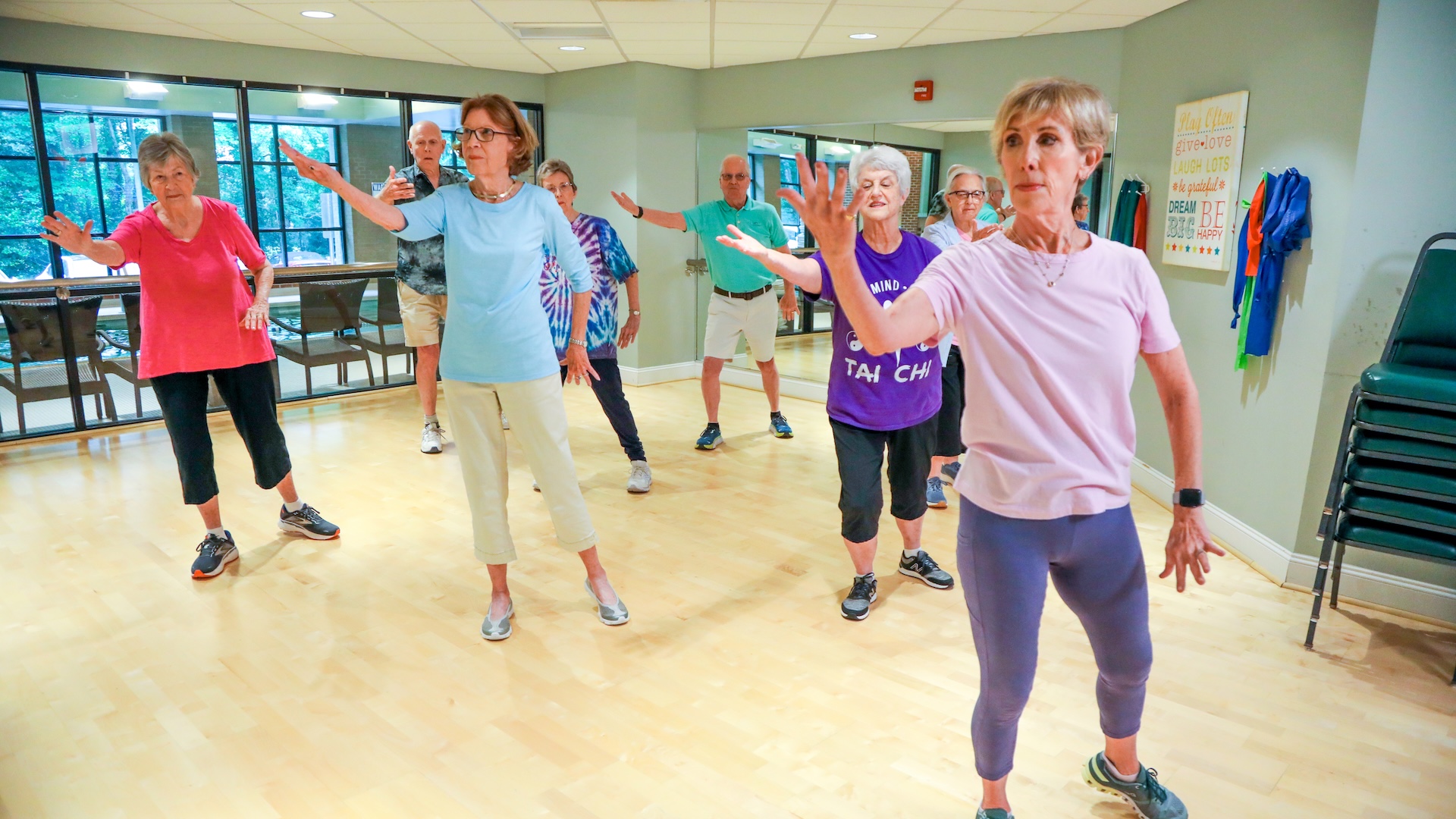 A group of seniors practicing Tai Chi in an indoor fitness studio.