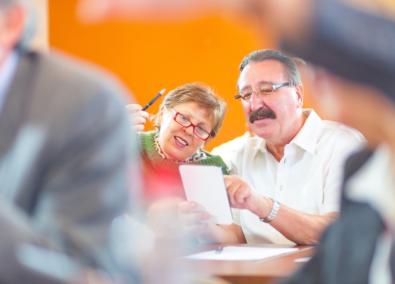 An older couple sitting together and looking at a digital tablet.